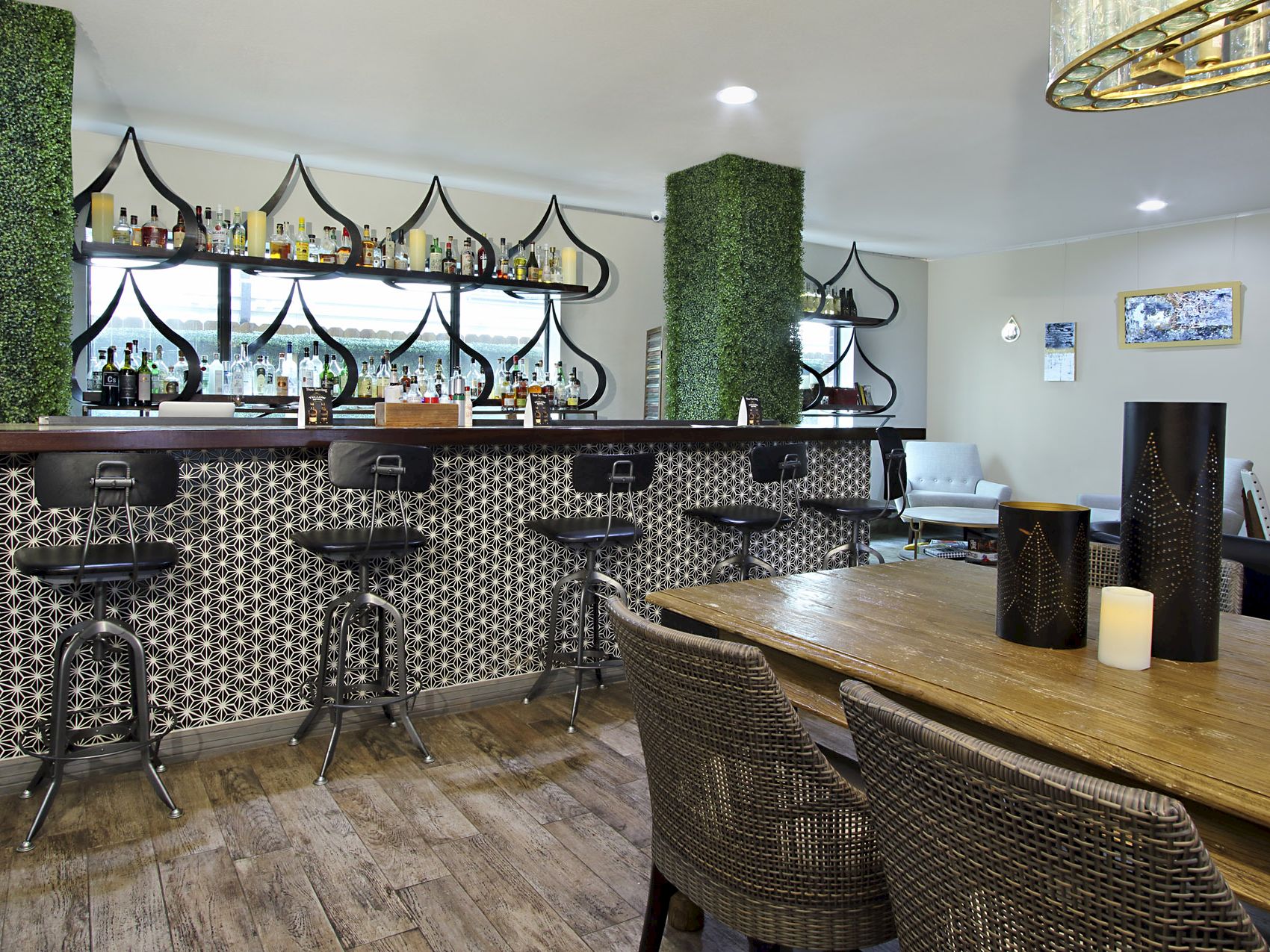 A bar with stools, a wooden table with wicker chairs, and a decorative interior