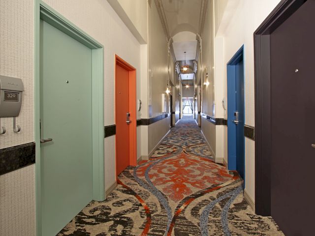 A long hallway with colorful doors and patterned carpet.