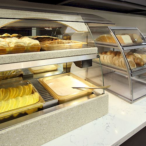 A display of assorted baked goods, including bread and pastries, arranged in glass cases on a countertop, likely in a café or bakery.